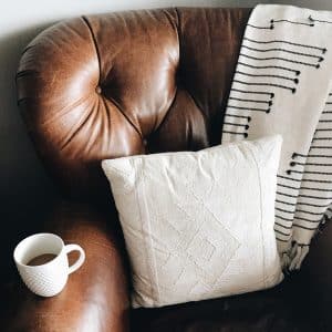 Photo of leather brown armchair with coffee cup and blanket