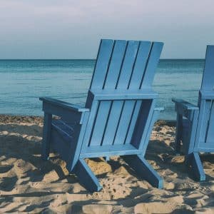 Photo of blue chair on the beach facing water